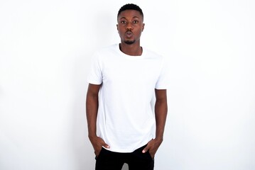 Portrait of lovely funny young handsome man wearing white T-shirt over white background sending air kiss