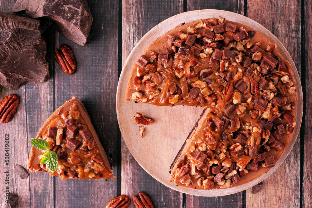 Poster delicious chocolate caramel pecan cheesecake with slice removed. top down view table scene on dark w