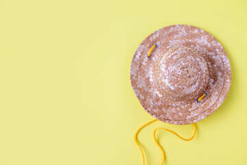 straw hat for leisure on yellow background, copy space