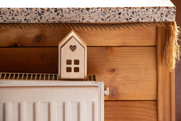 A small wooden house stands on batteries in an apartment near the window, a warm house