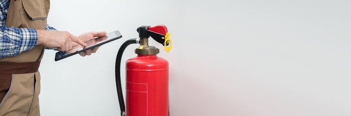 Fototapeta na wymiar Technician Using Digital Tablet To Check Fire Extinguisher