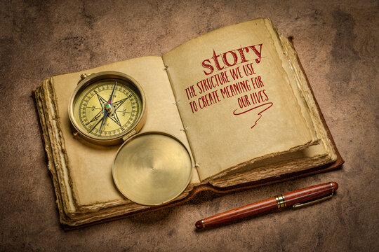 story - the structure we use to create meaning for our lives handwriting in a retro journal with a brass compass, storytelling and interpretation of reality concept