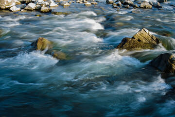 Flow, for a stormy river among the rocks in the autumn park on a warm day © chernikovatv