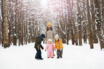 Happy family playing and laughing in winter outdoors in the snow. City park winter day.