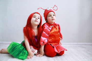Children in smart carnival costumes on a plain background. Costume of sea fairy creatures. Mermaid and crab.
