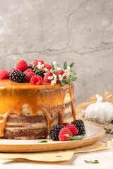 Delicious chocolate cake topped with mascarpone cream and salted caramel. Decorated with red fruits. Light background