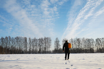 Hiking winter landscape. A man with a backpack travels in winter. A man in a snowy field.