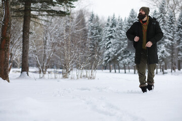Fototapeta na wymiar Outdoor portrait of handsome man in coat and scurf. Bearded man in the winter woods.