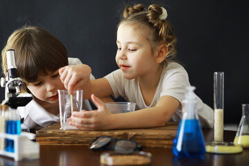 Children scientists. Schoolchildren in the laboratory conduct experiments. Boy and girl experiments with a microscope.