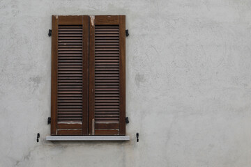 Obraz na płótnie Canvas Window with brown wooden shutters on the grey cement wall, background with space for text