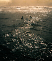 Surfers catching waves near a spanish beach during sunset 