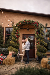 Young beautiful happy smiling couple standing near decorated house for Christmas. Christmas, New Year, winter holidays.