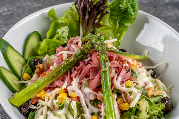 Green salad with vegetables,olives,cheese,salami and asparagus.