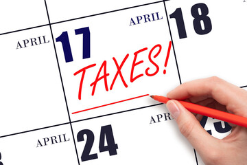 Hand drawing red line and writing the text Taxes on calendar date April 17. Remind date of tax payment