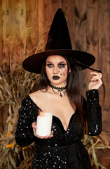 young girl in the image of a witch, wearing a black hat and a black dress with a make-up