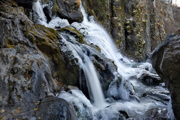 Fototapeta premium Russia. South of Western Siberia. One of the most beautiful waterfalls of the Altai Mountains on the Karasu River near the village of Chibit on the Chui tract, chained with ice of autumn frosts.