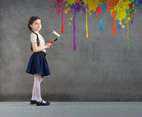 cheerful smiling young little girl the child draws on the background wall colored paints making a creative repairs