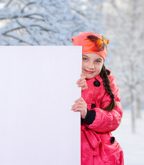 Smiling little young girl child in winter clothes jacket coat and hat holding a blank billboard banner white board
