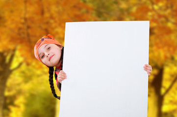 Smiling little young girl child in autumn clothes jacket coat and hat holding a blank billboard banner white board