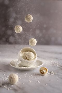 Winter background. Food art photography. Levitating coconut candies on a light gray background. Sweets, calories. Gray background. Levitation.