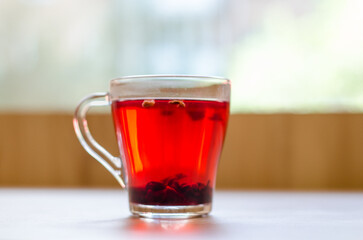 Red berry tea in a transparent cup on the background of a wooden table in a cafe