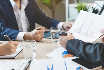 Close up hands of a businessman holding graph paperwork on the meeting conference table.