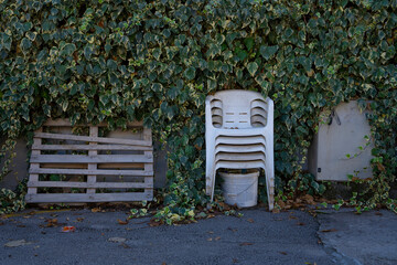 a white plastic chairs thrown out by people on the street near the forest. Pollution of the environment by plastic, A summer plastic chair stands in nature.