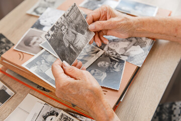 Senior woman is looking her own old photos at home. Elderly woman has got smile while remembering...