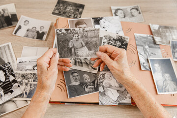 Senior woman is looking her own old photos at home. Elderly woman has got smile while remembering...