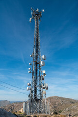 Telecommunications tower set among mountainous landscape.
