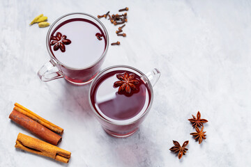 Obraz na płótnie Canvas Mulled wine in cups with anise, cinnamon and cloves on concrete background. Hot drink with wine, fruits and spices. Copy space. Top view