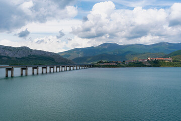 Obraz na płótnie Canvas Riaño Reservoir, with the town in the background, and the long viaduct that crosses the reservoir to reach the town, surrounded by high peaks.