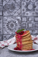 A stack of delicious pancakes with cranberries and berry sauce on a gray kitchen table. Pancakes...