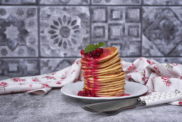 A stack of delicious pancakes with cranberries and berry sauce on a gray kitchen table. Pancakes...