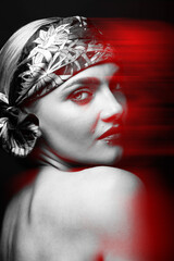 Studio portrait of beautiful and sexy woman with scarf on her head in red color split effect. Model looking at camera through shoulder and naked back. Black and white image. Futuristic looking style