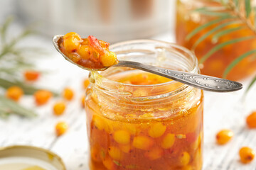 Jar of healthy sea buckthorn jam. A spoonful of buckthorn jam close up. A pot, jam jar and sea...