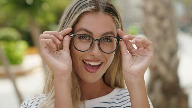 Young blonde woman smiling confident wearing glasses at street