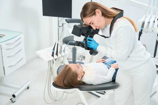 Pediatric dentist taking images of child mouth during consultation