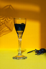 Halloween minimal concept, idea. Spider net shadow, glass, spider on yellow table.