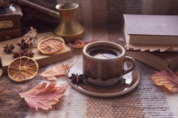 Autumn mood, autumn atmosphere. A cup of hot coffee, cinnamon sticks, star anise, a book, autumn...