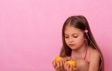 Caucasian beautiful little girl with fresh yellow lemons on a pink background. Little girl with lemon. Funny child isolated on pink.