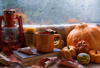 Autumn mood, autumn atmosphere. A cup of hot coffee, a book, a lamp, autumn leaves and pumpkins on...