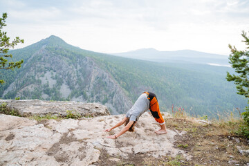 Adho mukha shvanasana, flexible back, strengthening of the spine, the guy practices yoga in nature, mountain top, meditation in asana, slide.