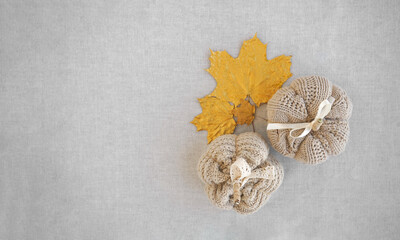 Hobby background with handmade knit pumpkins and golden maple leaves. DIY, craft decoration for fall and winter holidays. Flat lay, top view