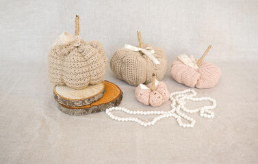 Hobby background with handmade knit pumpkins and white pearl beads. DIY, craft decoration for fall and winter holidays.