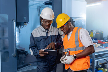 Team african american engineer in uniform using tablet computer for control CNC machinery on industry car factory