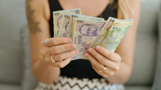 Young woman counting romania ley banknotes at home