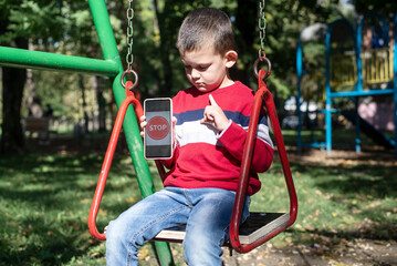 Scared little boy shows stop on the phone. Internet violence against children