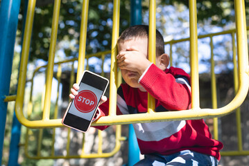 Children holding a smartphone and showing a stop sign with his hand, Stop cyber bullying concept, mental health problem - obrazy, fototapety, plakaty