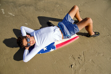 Teenage boy at the beach lying down on his boogie board